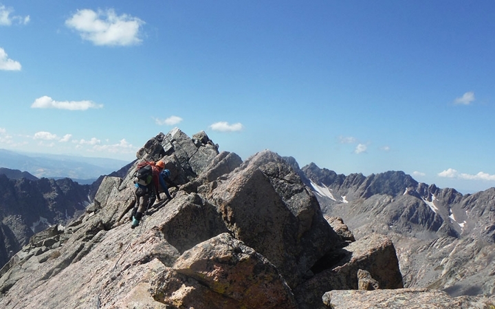 outward bound students wearing safety gear make their way along a high rocky ridge